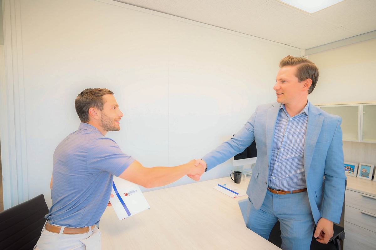 Two colleagues shaking hands across a desk