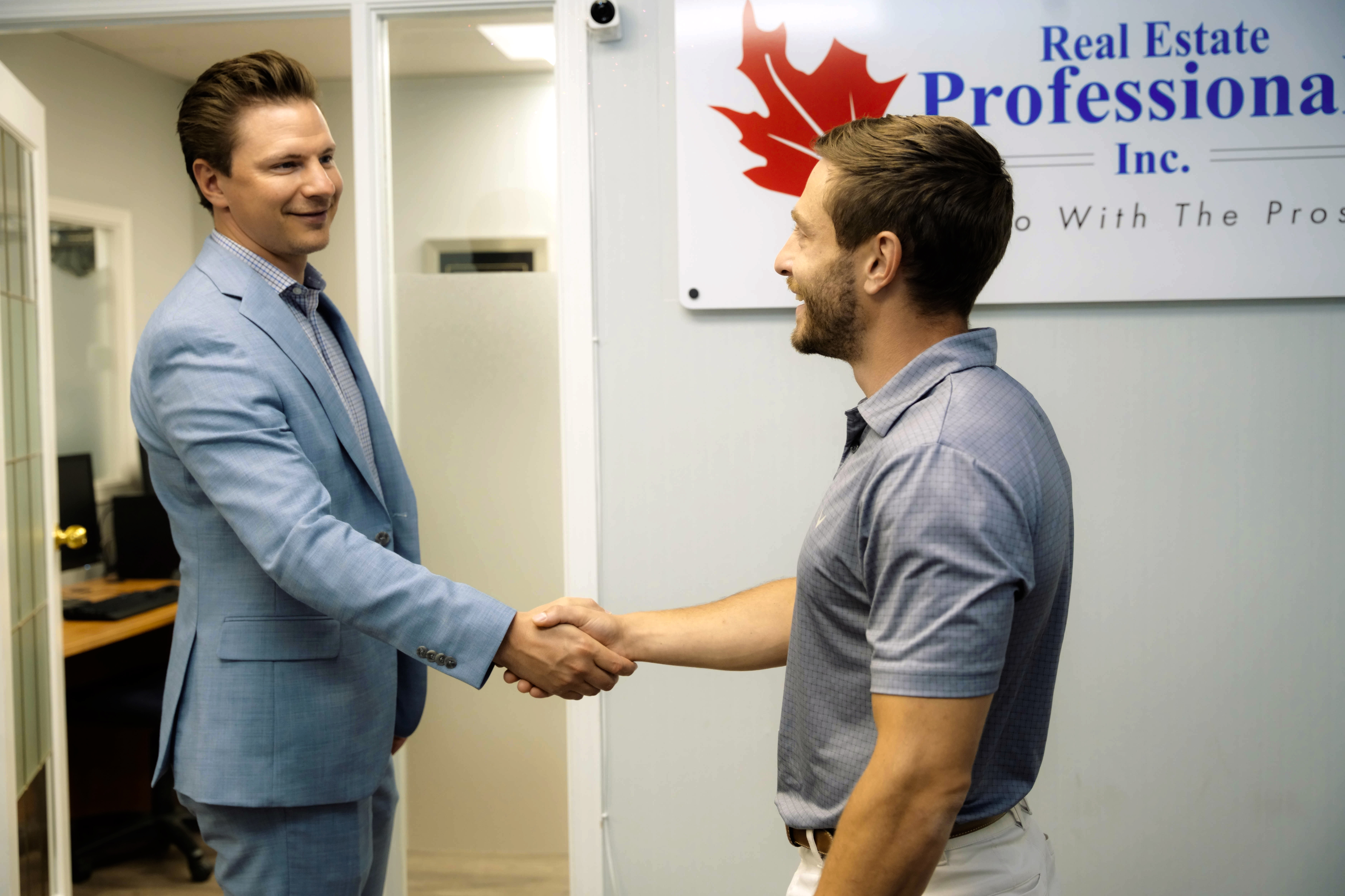 Two colleagues shaking hands in the Real Estate Professionals Inc. office
